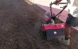 Preparing top soil for turf laying using a rotary hoe